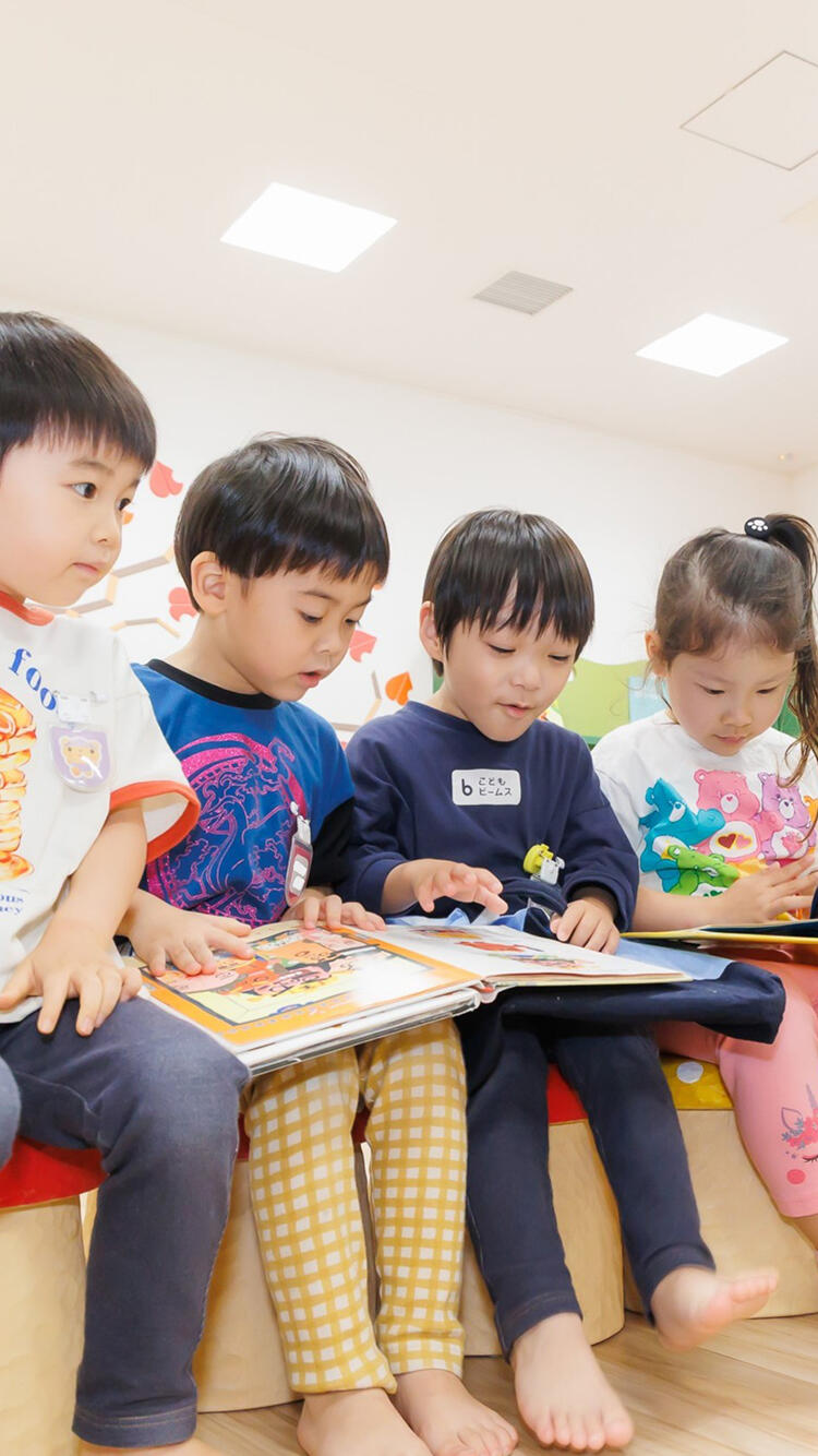4人の園児が座って本を読んでいる様子